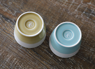 浅葱色と亜麻色のそば猪口を底面の卯月製麺のロゴが見えるように並べた写真。