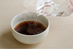 器に注いだ添付の「鴨だしつゆ」にお湯を注いでいる写真