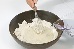 少しずつ水を注ぎながらそば粉をかき混ぜている写真