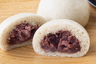 そば饅頭を縦に半分に割ってぎっしり詰まった餡子を見せている写真