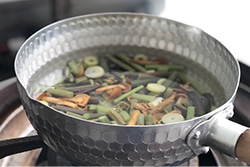 鍋で山菜を湯がいている写真