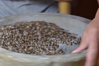 石臼でソバの実を挽いている写真