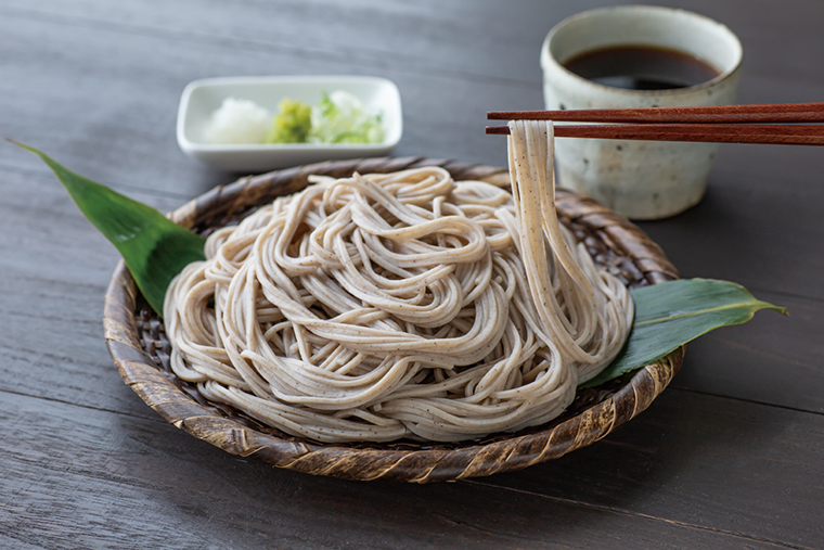 石臼挽き新そばをざるに盛り箸で持ち上げている様子