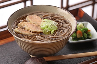 お盆の上の器に冷たい肉そばと薄く輪切りにしたネギと鶏肉を乗せた写真